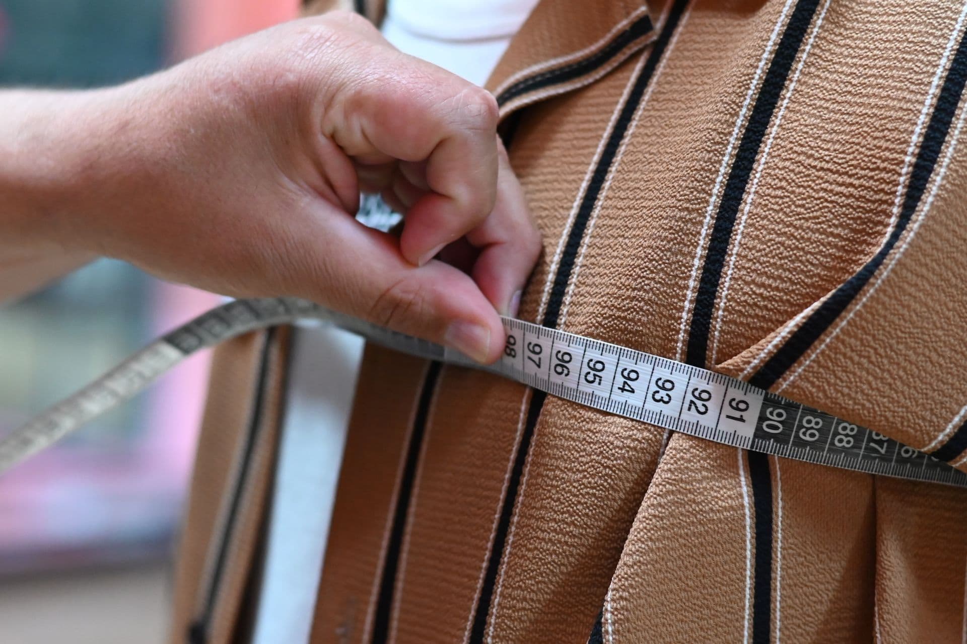 Hands measuring fabric with a tape to verify yardage before cutting